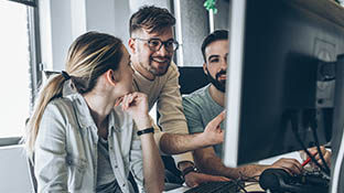 Gruppe von Menschen, die vor einem Computer zusammenarbeiten